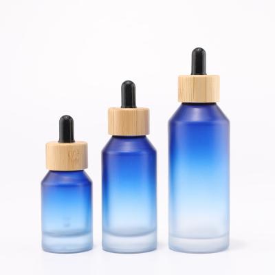градиентная бутылка из синего стекла с бамбуковой капельницей для косметической упаковки
